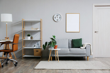 Interior of room with modern furniture, clock and blank photo frame on wall