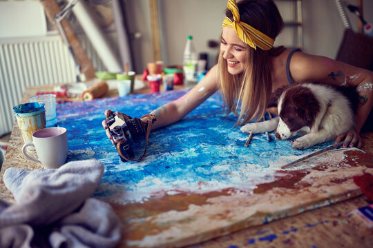 Young cute female artist playing with her dog