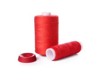 Red thread spools and button on white background