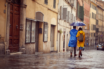 Man and woman in raincoats are walking in the rain
