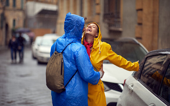 A young couple in love is enjoying the rain while walking the city on a rainy day. Walk, rain, city, relationship