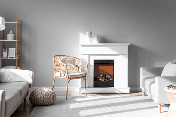 Interior of light living room with wicker armchair and fireplace