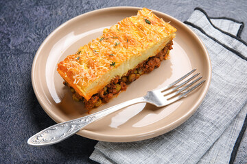 Plate with piece of tasty Shepherd's pie on black background