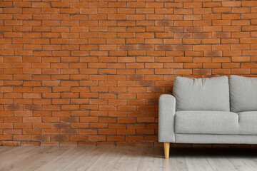 Stylish sofa near brick wall