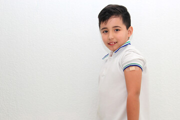 8-year-old Hispanic boy wearing a school uniform shirt happily shows his recently vaccinated arm against Covid-19 in the new normality due to the Coronavirus pandemic
 - obrazy, fototapety, plakaty
