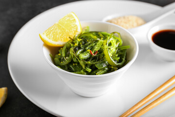 Bowl with healthy seaweed salad on dark background