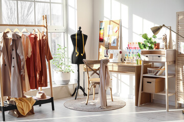 Interior of stylish atelier with tailor's workplace, mannequin and rack - obrazy, fototapety, plakaty