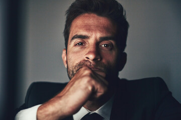 Mmm...I wonder. Cropped portrait of a handsome young businessman working late in the office.