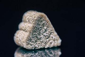A piece of refined sugar with cinnamon on a black background. Photographed close-up.