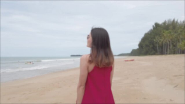 Blurred Young asian woman wear red dress and walking relaxing on the beach at summer vacation holidays in slowmotion