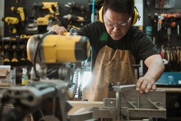 Carpenter cutting wooden with a miter saw or circular saw in shop, woodworking repair and construction tool concept ,selective focus