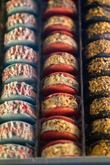 Assortment of colorful french macaroons on cafe showcase for sale . Variety of macaron flavours. Sweet almond cakes in store. Cookies in the shop on storefront. Top view. 