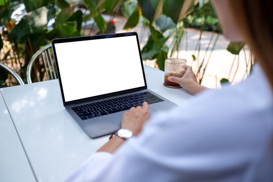 Mockup image of a woman using and working on laptop computer with blank white desktop screen while drinking coffee