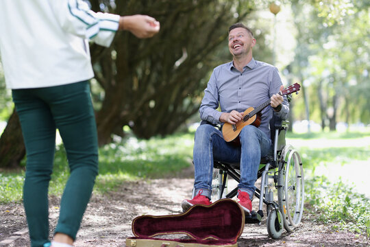 Man In Wheelchair Sings For Money On Guitar In Park