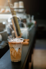 Ice coffee on a plastic cup with cream being poured into it showing the texture