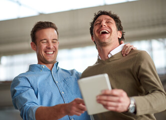 Take time out for a good old laugh. Male coworkers laughing out loud about something humorous on a...