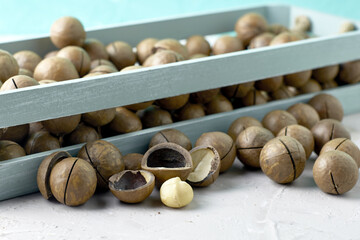 macadamia nuts in a vintage wooden box next to scattered nuts