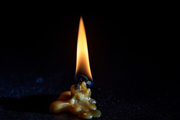 The flame of a dying candle on a dark background.