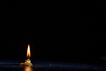 The flame of a dying candle on a dark background.