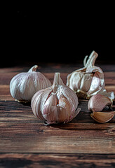 Fresh garlic bulbs and a garlic press on an old wooden board and a burlap backing.