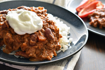 Chilli con carne with minced beef, red kidney beans, onion, paprika, cumin and herbs, with Greek yogurt on the top, and having it with rice.  Traditional Mexican food.