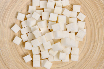Refined sugar in a wooden plate closeup.