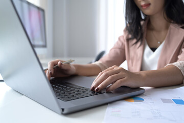 Young businesswoman hands typing on laptop computer while working at office desk.
