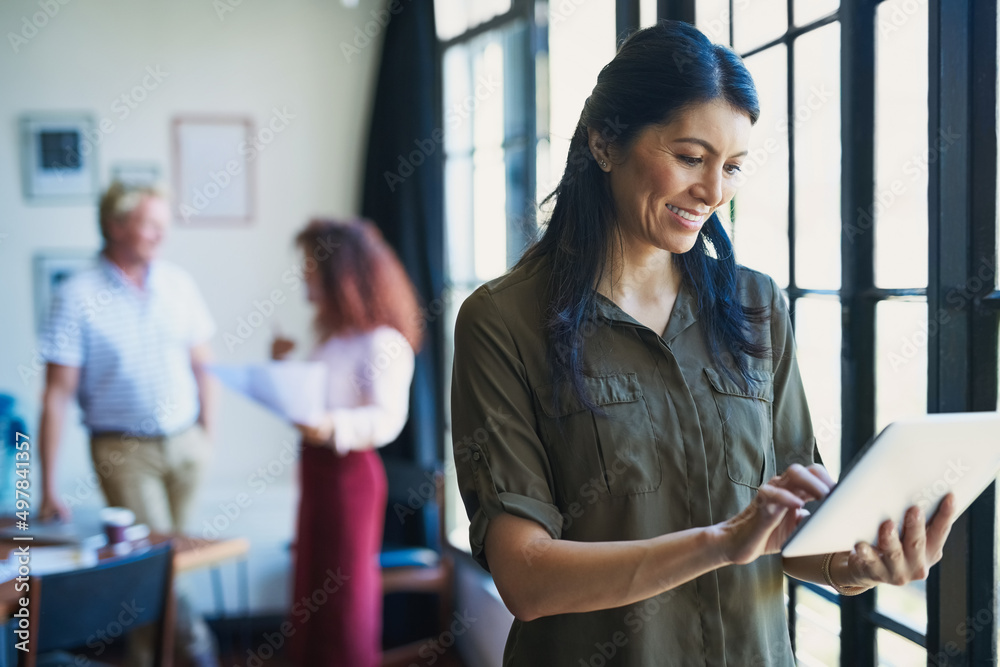 Poster management in the age of the app. shot of a mature woman using a digital tablet with her team in the
