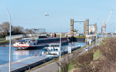 P&eacute;niche transportant des container sur un canal et devant une &eacute;cluse dans le port de Dunkerque