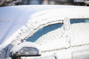 Car covered with a thin layer of fresh white snow. Side view.