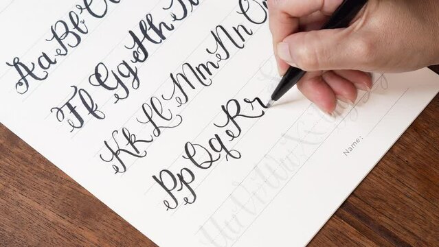 Handwriting exercise for beginners. Write with a black ink brush tip pen on white paper with faded shadows.