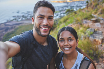 Memories to last a lifetime. Shot of a young couple taking photos while out on a hike in a mountain range outside.