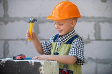 Kid in hard hat holding hammer. Little child helping with toy tools on construciton site. Kids with...