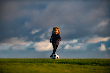 Boy kicking football ball. Soccer boy, child play football. School kids playing football in a field.