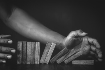 Close-up hand prevent wooden block falling domino concepts of financial risk management and strategic planning and business challenge plan.