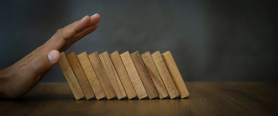 Close-up hand prevent wooden block falling domino concepts of financial risk management and...