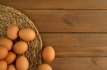 Fresh eggs on a woven seagrass mat or pad, with copy space on wooden panel planks background.