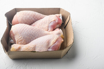 Batch chilled chicken drumsticks, in paper Pack, on white stone  background, with copy space for text