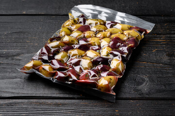 Pickled Olives in Vacuum Sealed Bag, on black wooden table background, with copy space for text