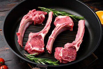 Uncooked mutton rack of lamb, on frying cast iron pan, on old dark rustic table background