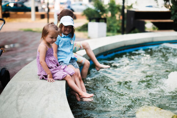 Happy European children play with water in the city fountain, child safety and freedom in the city....