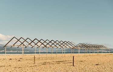 Old canopies from sun on a city pebble beach, Black Sea coast, empty calm beach on a sunny day. The...