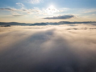 Flight over fog in Ukrainian Carpathians in summer. Mountains on the horizon. A thick layer of fog covers the mountains with a continuous carpet. Aerial drone view.