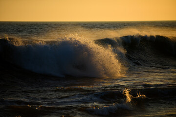 Sea waves background. Beach sunrise over the tropical sea. Colorful sunset with wave splashes on the beach.