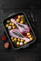 Raw turkey drumsticks with thyme, pepper, on black wooden table background, top view flat lay, with copy space for text
