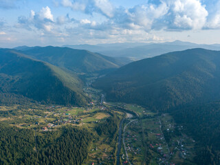Fototapeta premium Green slopes of Ukrainian Carpathian mountains in summer. Cloudy day, low clouds. Aerial drone view.