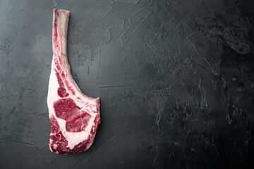Raw fresh tomahawk black angus prime beef chop steak, on black stone background, top view flat lay, with copy space for text