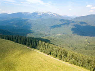 Green mountains of Ukrainian Carpathians in summer. Sunny day, rare clouds. Aerial drone view.