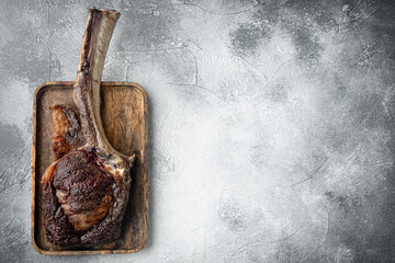 Barbecue dry aged Tomahawk Steak beef meat, on wooden serving board, on gray stone background, top...
