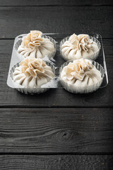 Homemade, traditional chinese pan fried dumplings, in plastic tray, on black wooden table background, with copy space for text